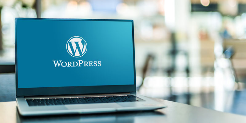 Laptop mit WordPress-Logo auf einem blauen Hintergrund auf dem Bildschirm.